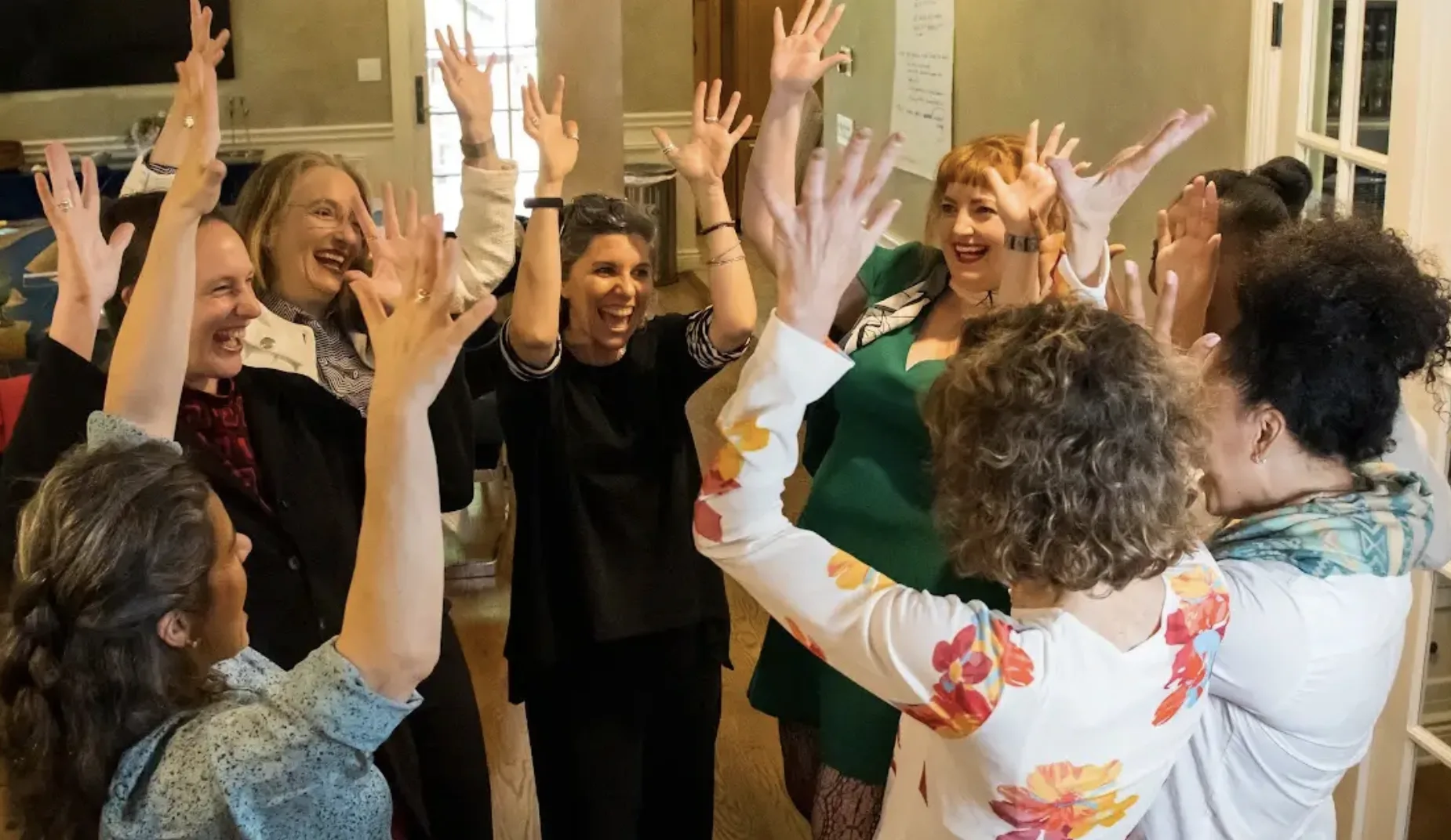 A Lab cohort standing together with their hands raised, laughing
