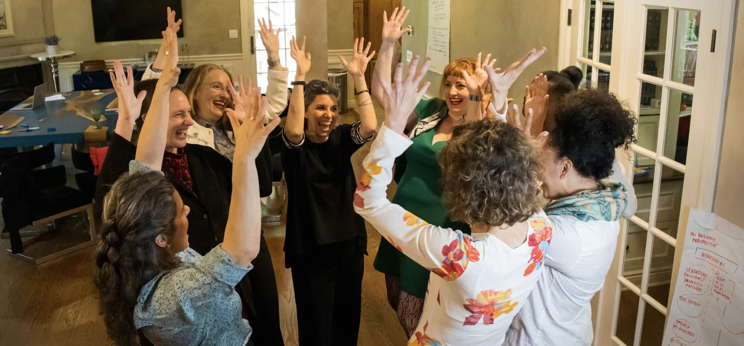 Women in a leadership session, hands raised, mid-exercise